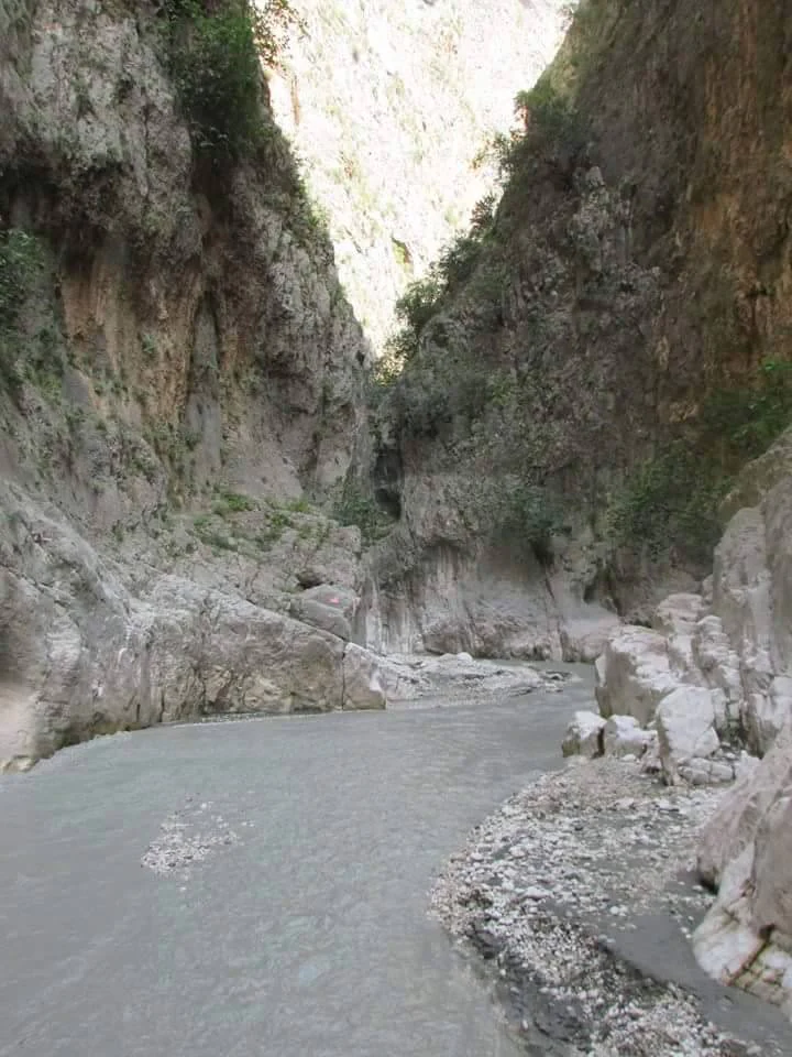 A wide view of Saklıkent Canyon with steep rocky cliffs and a river flowing through the canyon
