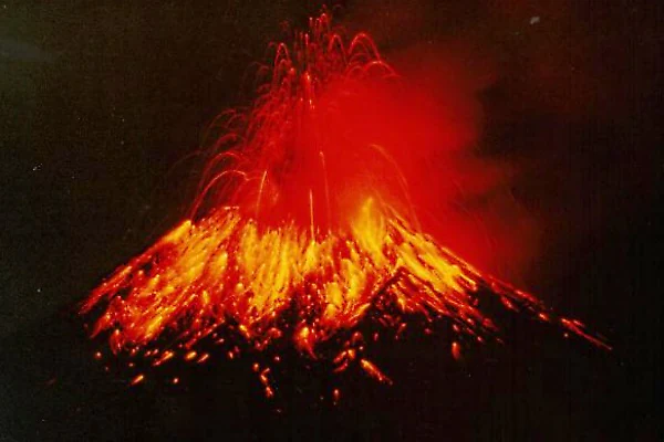 Volcanic eruption showing bright orange lava flows and red ash plume against dark sky