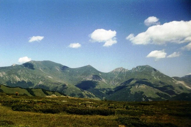 Mountain landscape view showing multiple peaks under blue sky with scattered clouds