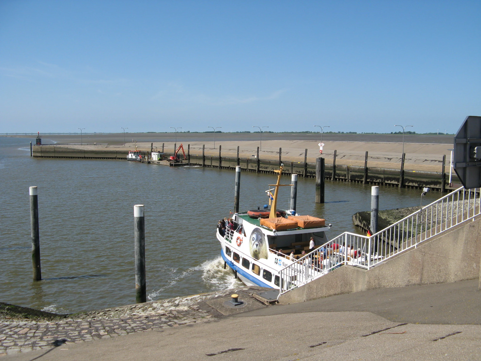 Ferry boat exiting lock structure at Eider Barrage with calm water and blue sky