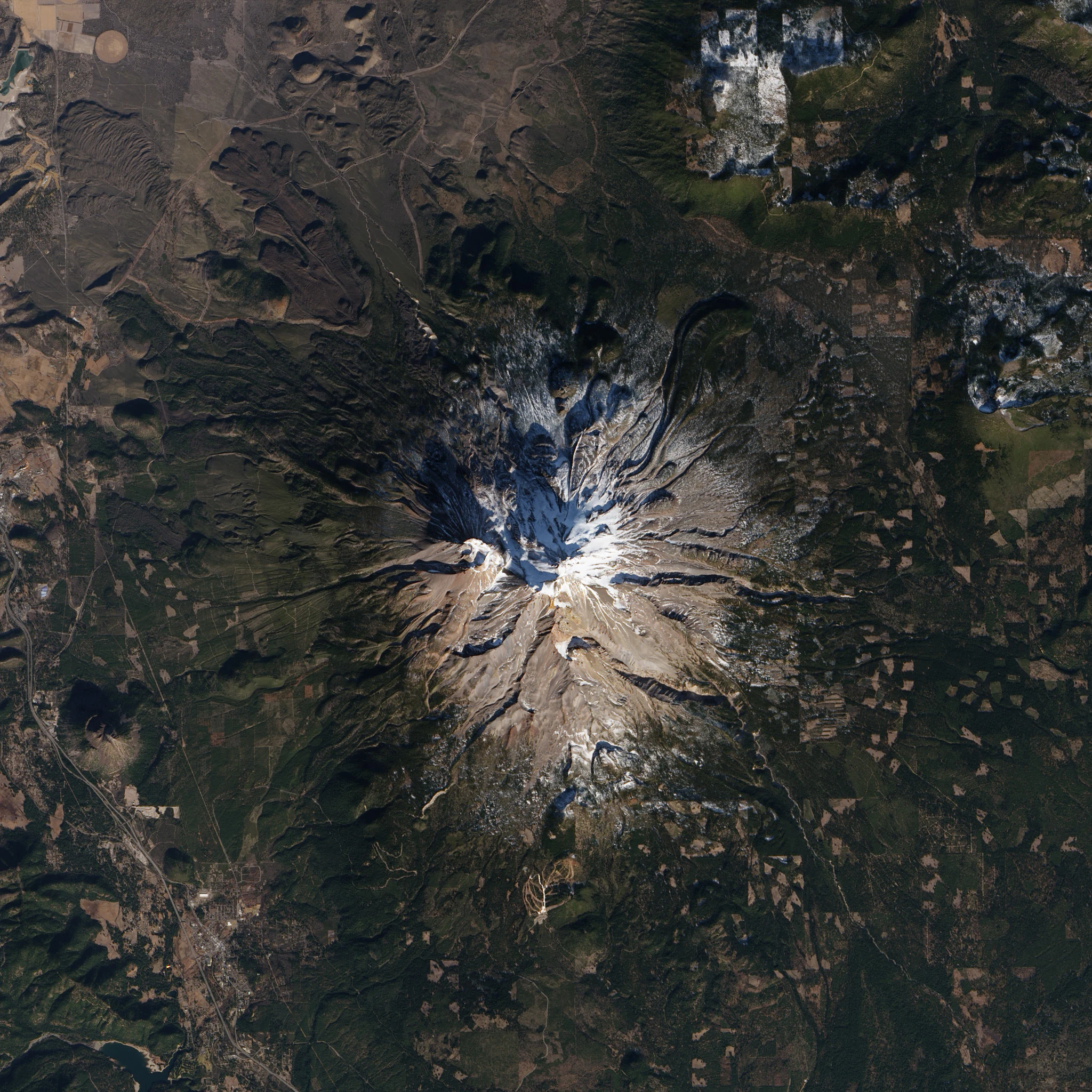 Satellite imagery showing the snow-capped peak of Mount Shasta and the surrounding forest terrain.