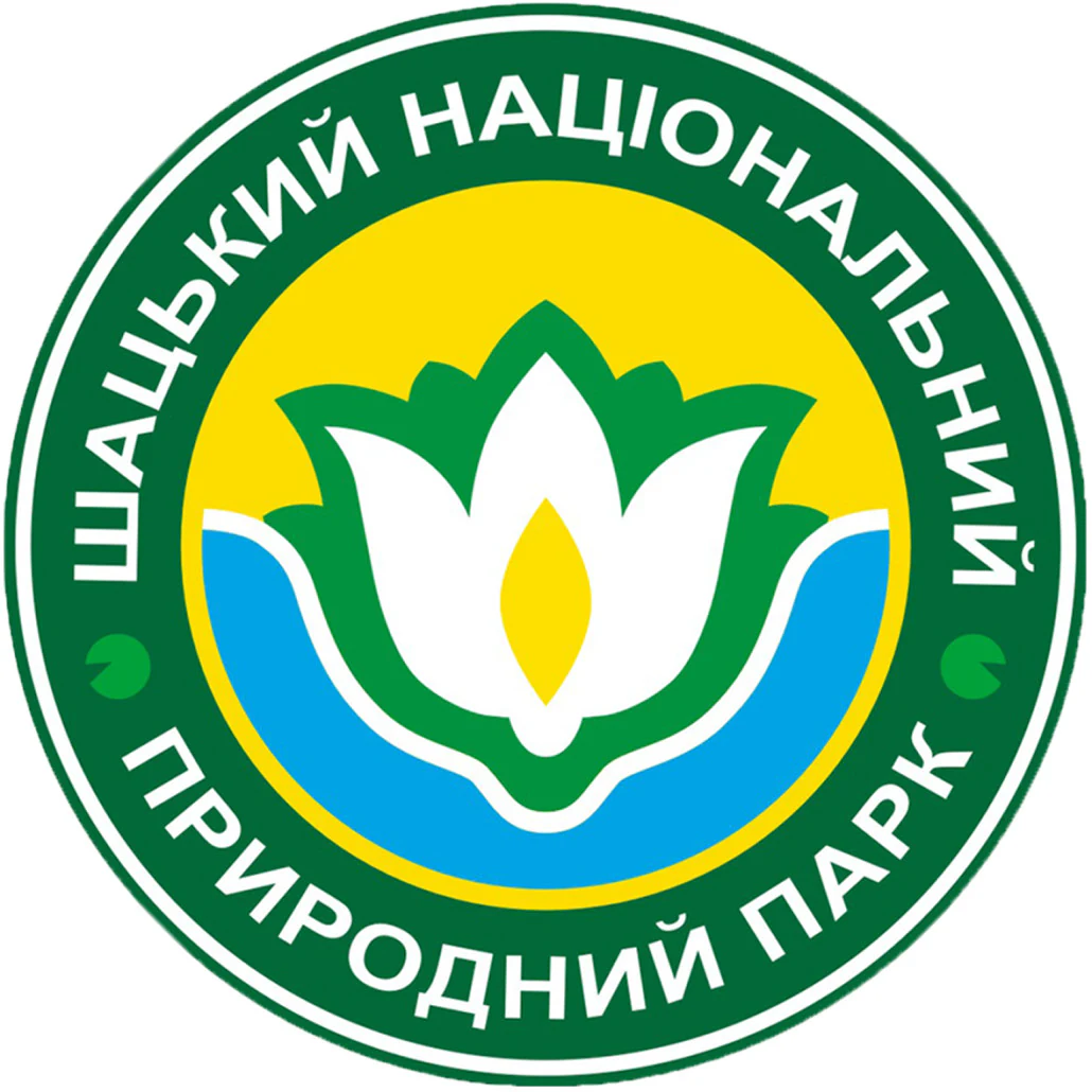 Circular emblem with Ukrainian text 'ШАЦЬКИЙ НАЦІОНАЛЬНИЙ ПРИРОДНИЙ ПАРК', green and yellow border, white and green flower, blue water elements