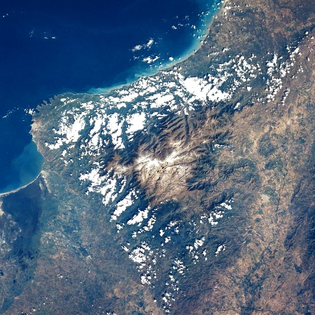 Imagen satelital que muestra la cordillera de la Sierra Nevada de Santa Marta con áreas costeras y cubierta de nubes dispersas