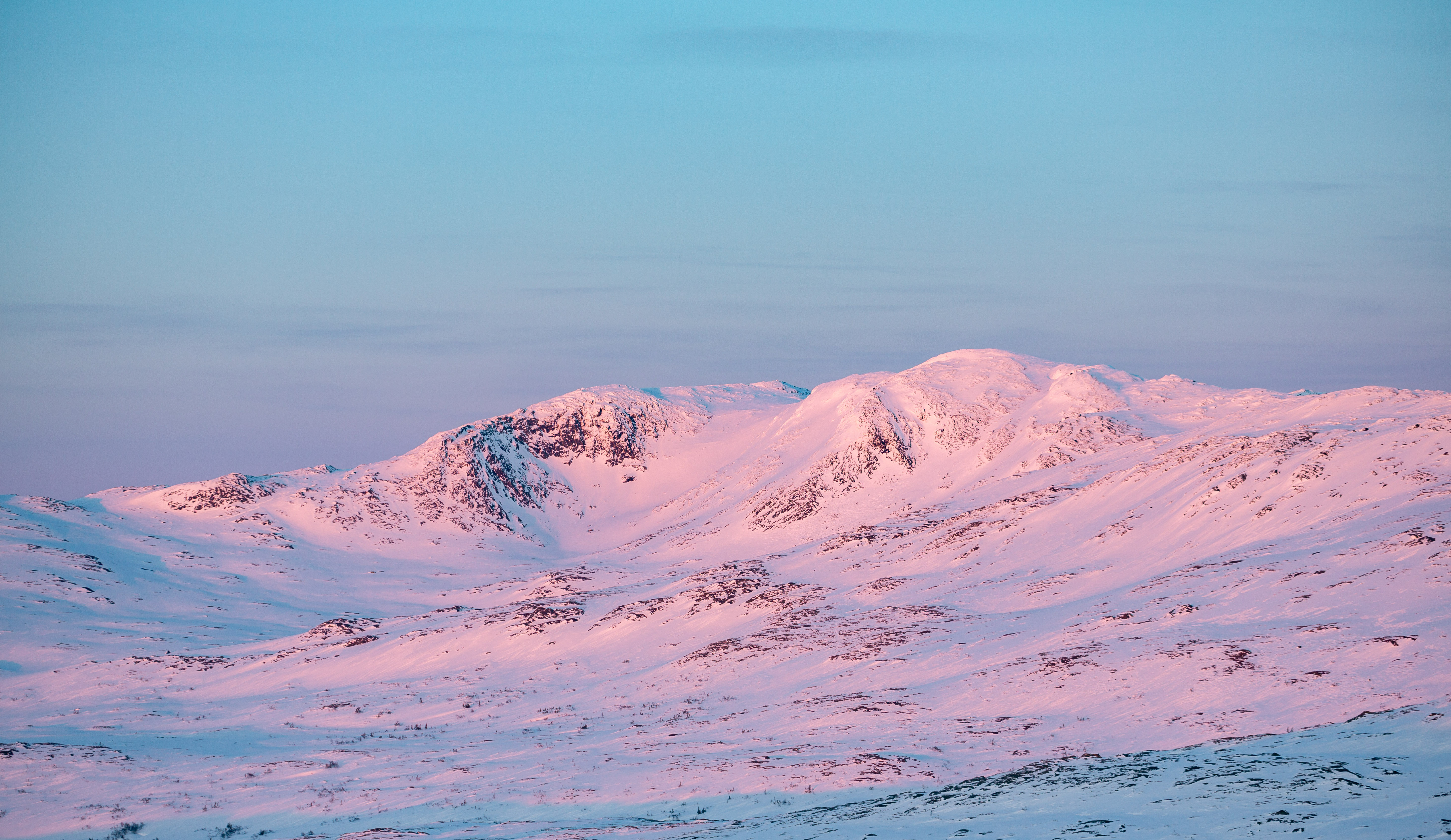 Snow-covered mountain peaks under a pink and blue sky at sunset