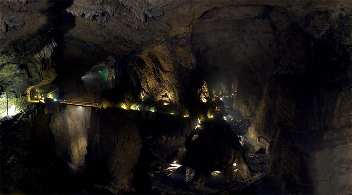 Underground cave interior with lit walkway, rocky walls, and artificial lighting