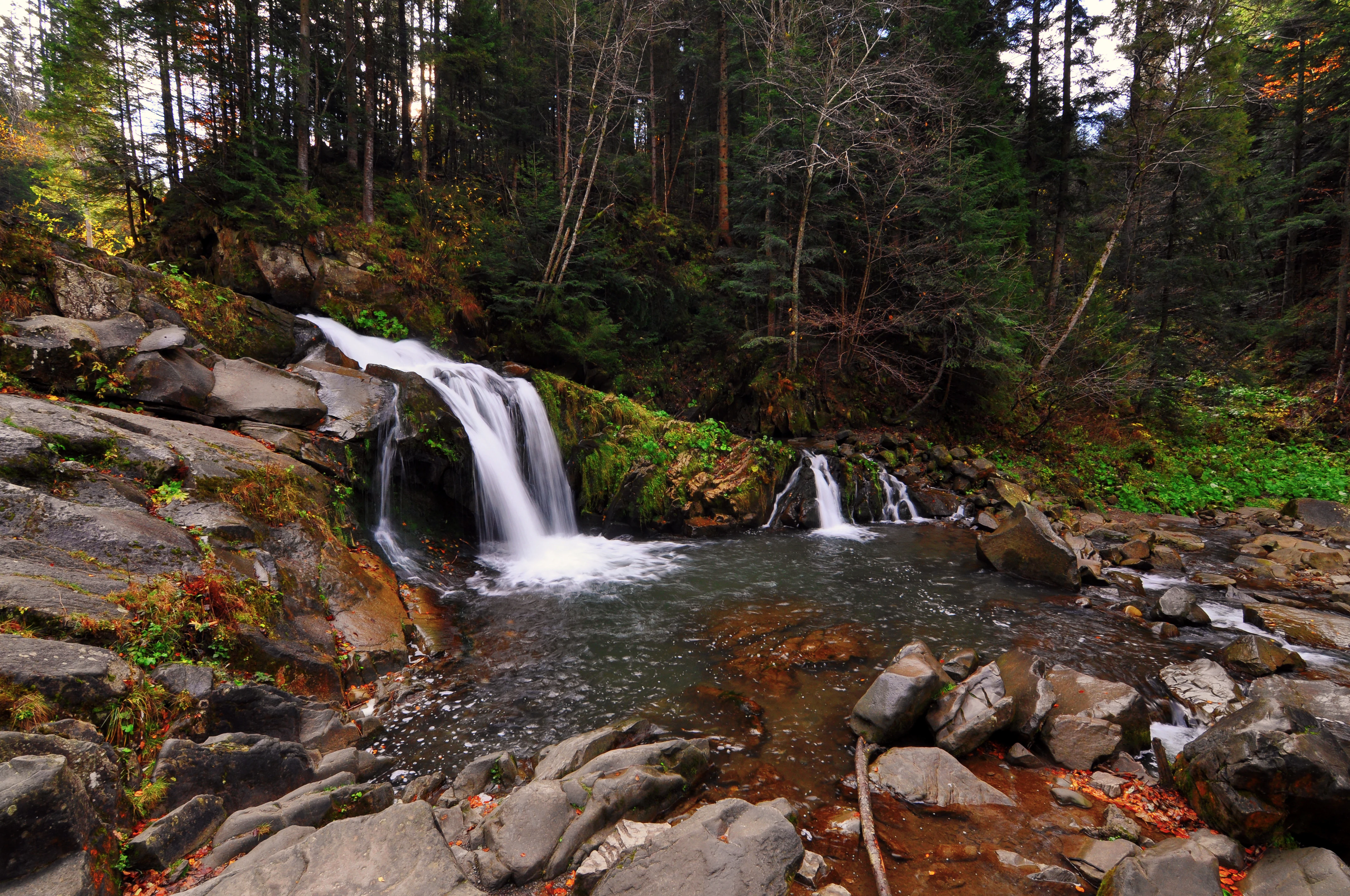 Waterfall cascading over rocks in a forested area with green vegetation
