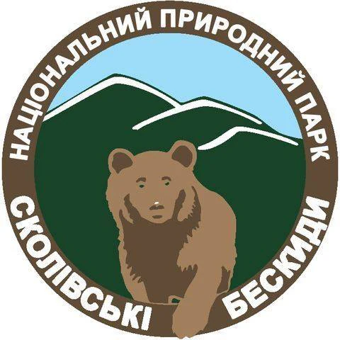 Circular emblem with brown bear in center, green background, blue sky, and Ukrainian text around border