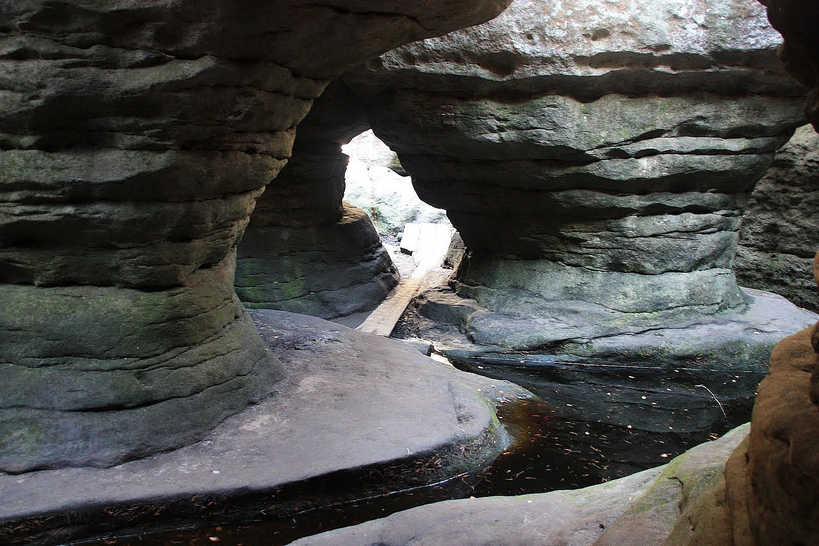 Sandstone rock formations with narrow passages and a wooden walkway in a natural park setting