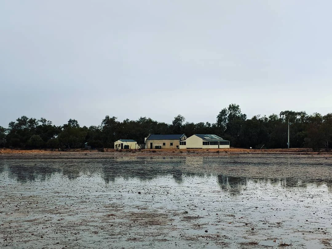 Two small buildings on a wetland with tree reflections in shallow water