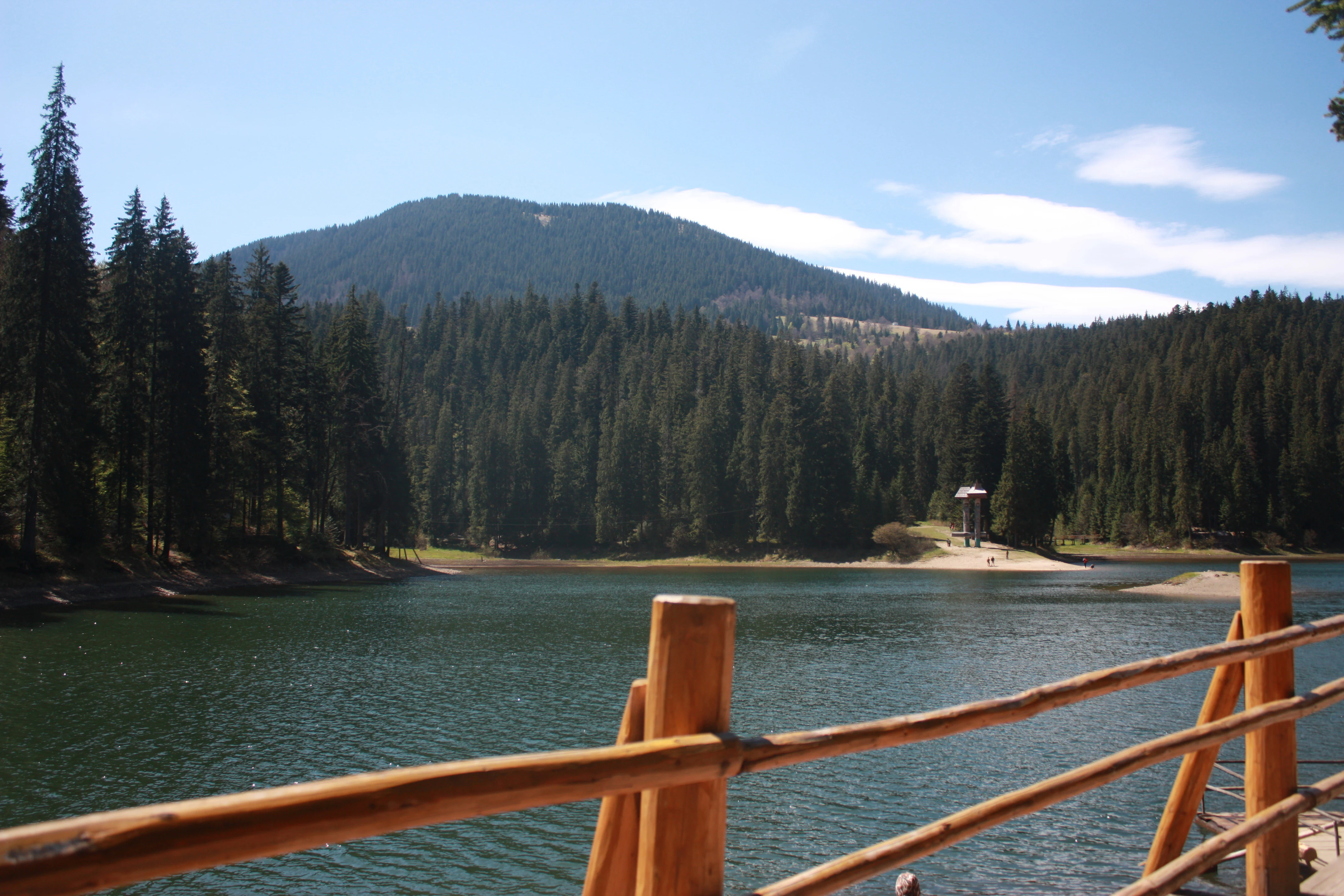 Wooden railing overlooking Synevyr Lake with forested mountains in the background