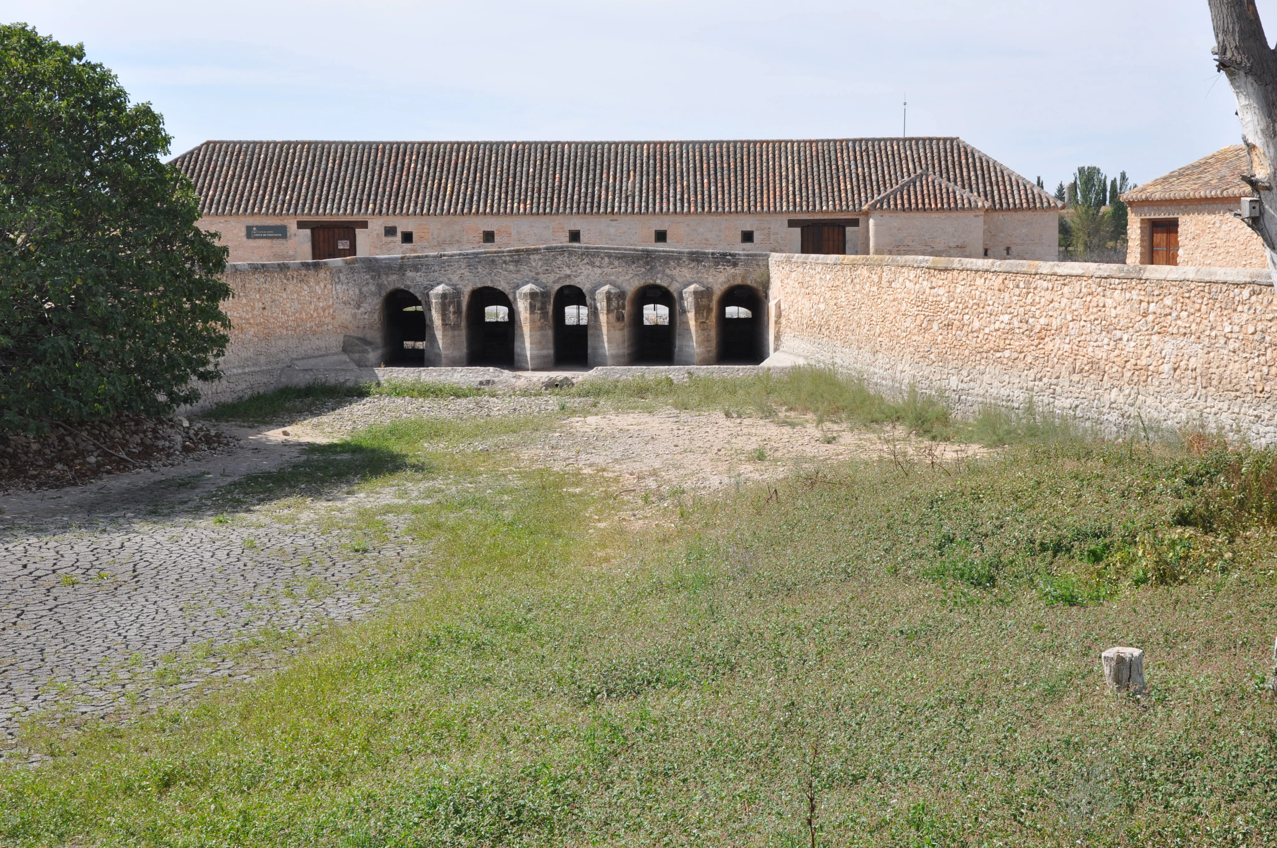 Stone mill building with arched openings and tiled roof surrounded by grassy field in Tablas de Daimiel National Park