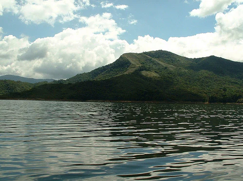 Calm lake water reflecting mountain peaks and a partly cloudy sky