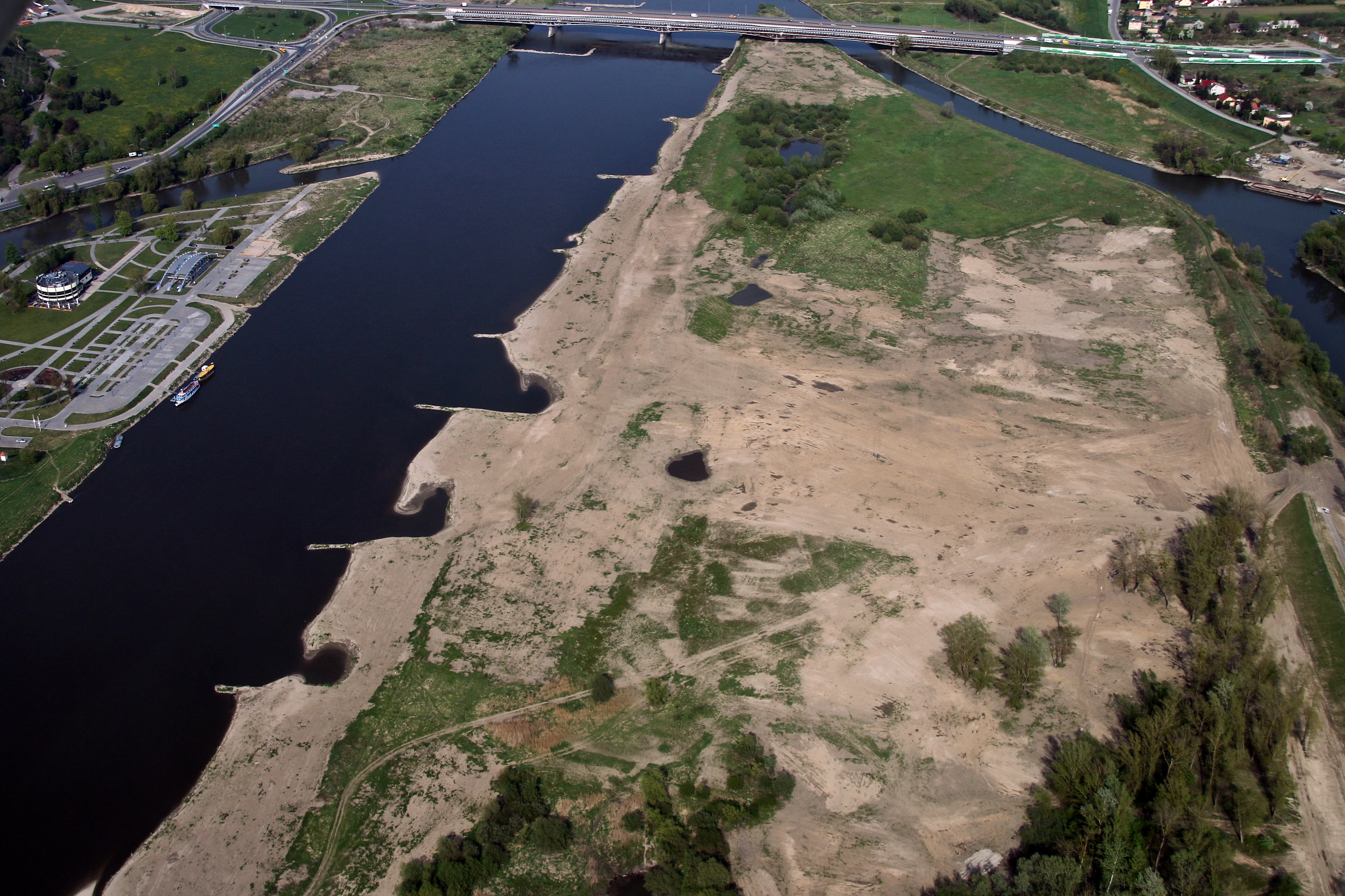 Una vista aérea del río Vístula con una orilla arenosa, riberas y un puente a lo lejos.