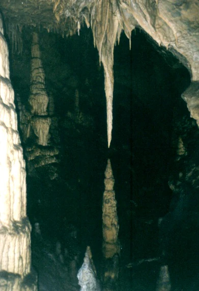 Estalactitas y estalagmitas en el interior de una cueva con paredes rocosas y luz tenue