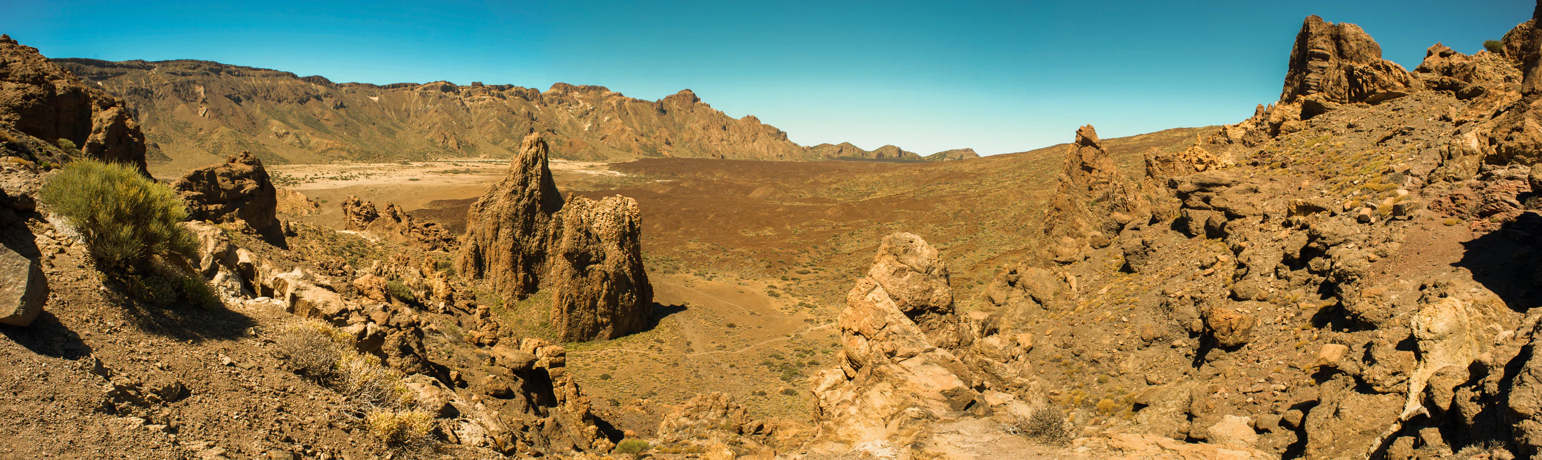 Panoramic view of rocky volcanic rock formations and arid terrain in Teide National Park, Canary Islands.