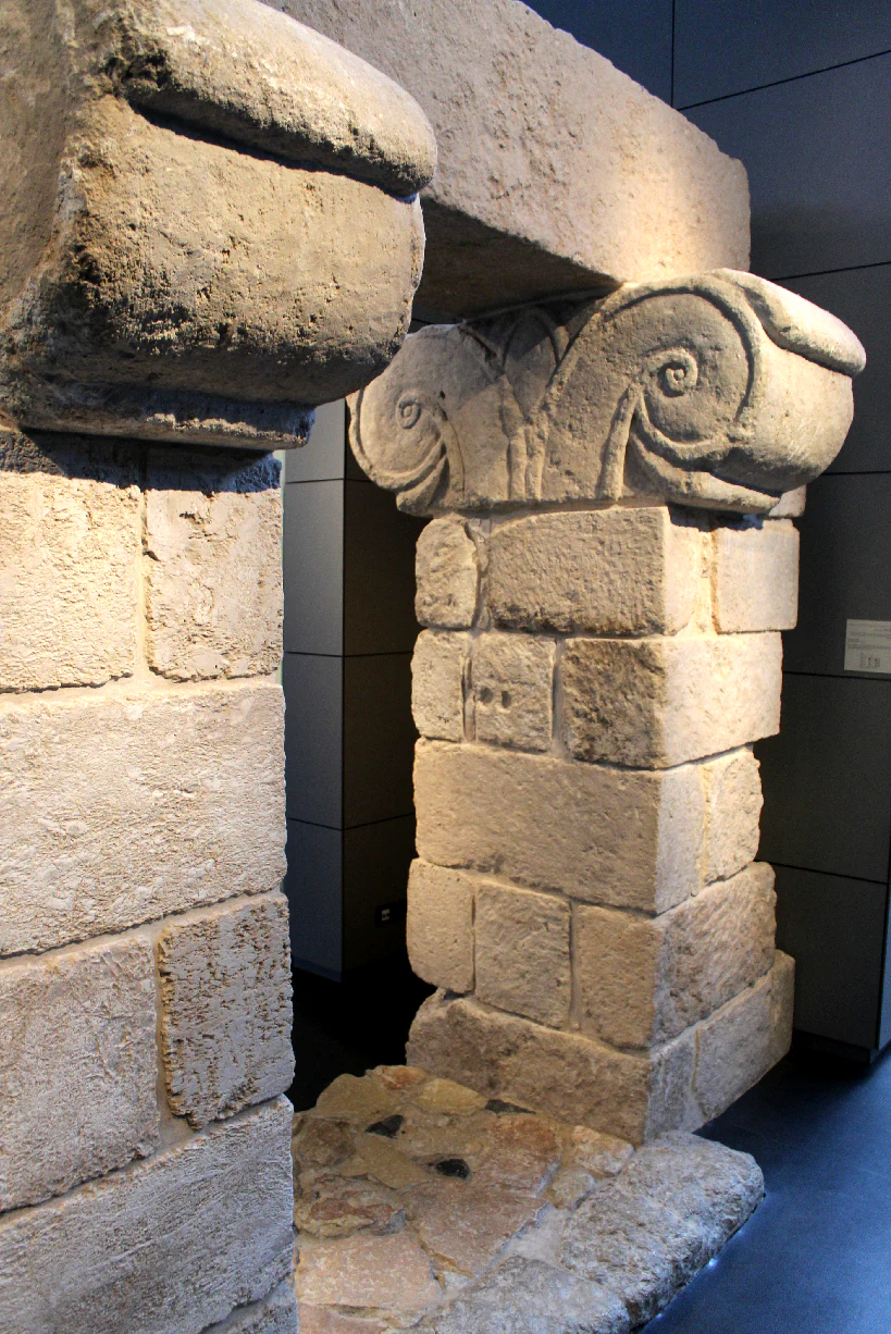 Stone architectural structure with carved scroll designs displayed indoors