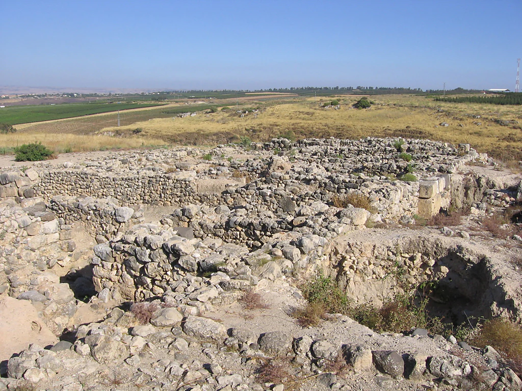 Stone ruins of an ancient archaeological site with scattered walls and foundations under a clear blue sky