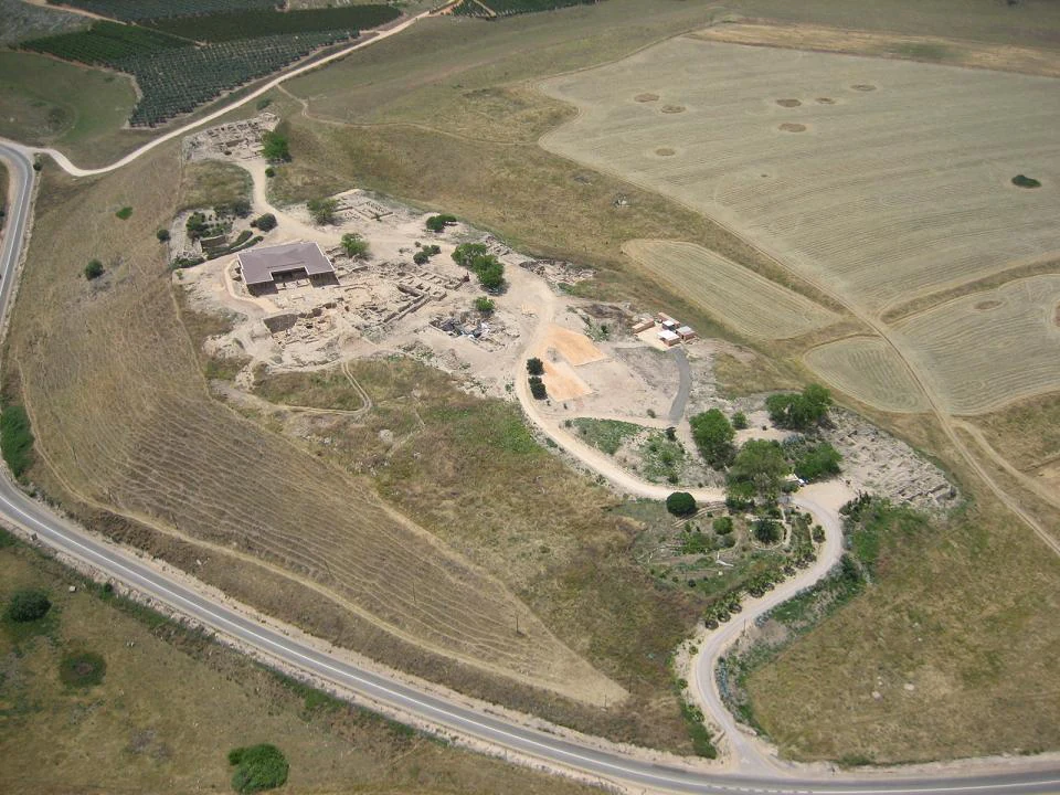 Aerial photograph of Tel Hazor National Park showing archaeological ruins, a building, roads, and surrounding agricultural fields
