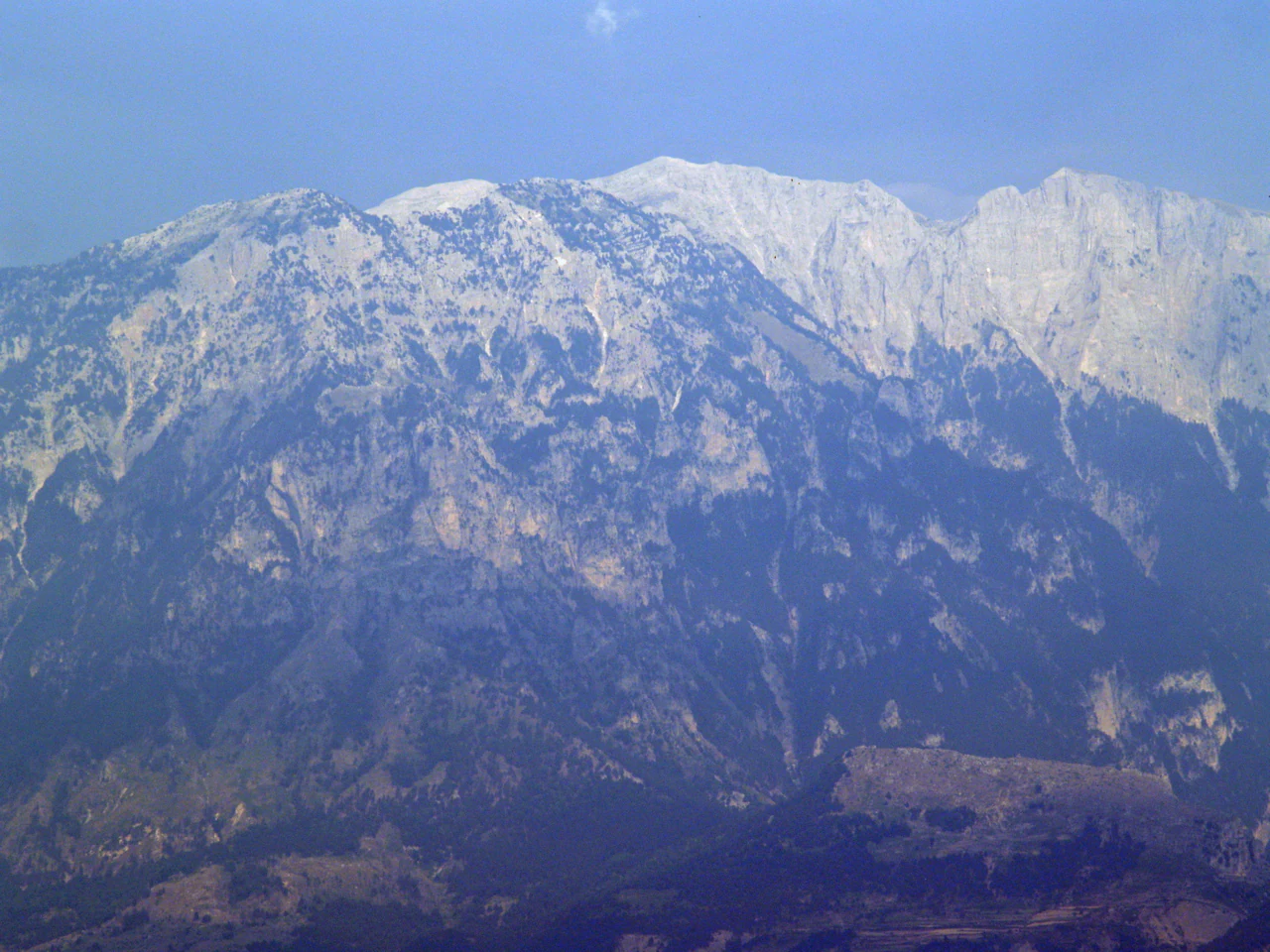 Snow-capped mountain range with rocky terrain under a clear sky