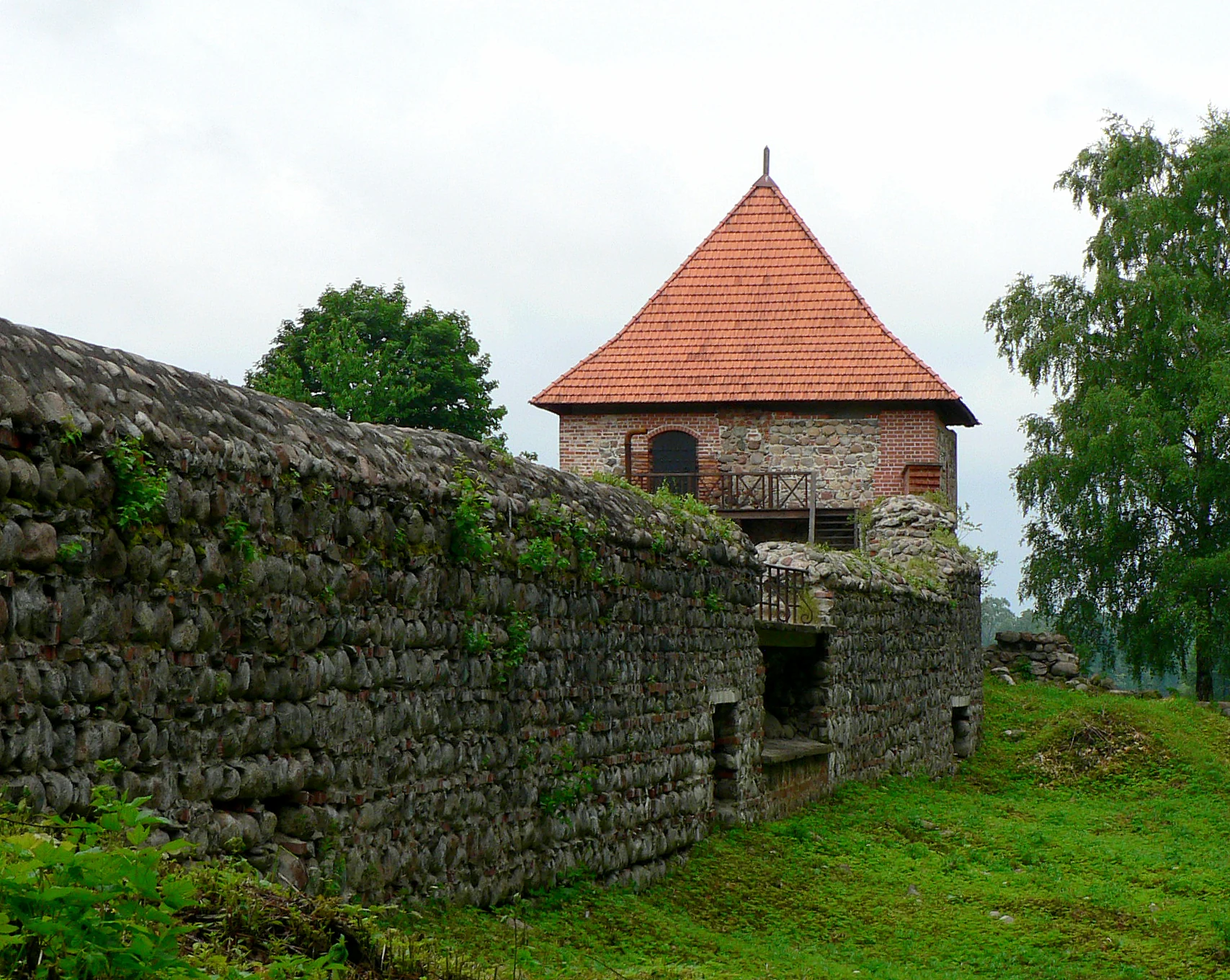 Historic stone wall and red-tiled tower in Trakai National Historic Park.