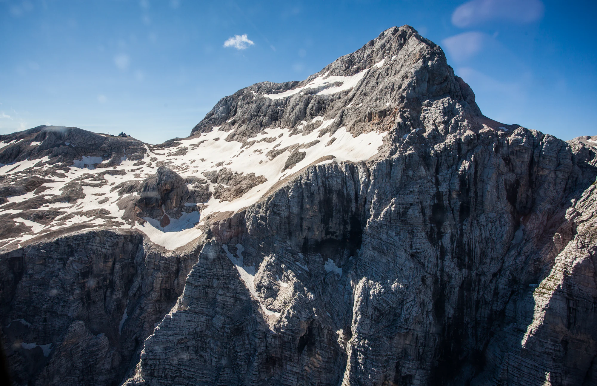 Rocky mountain peak with patches of snow under clear blue sky
