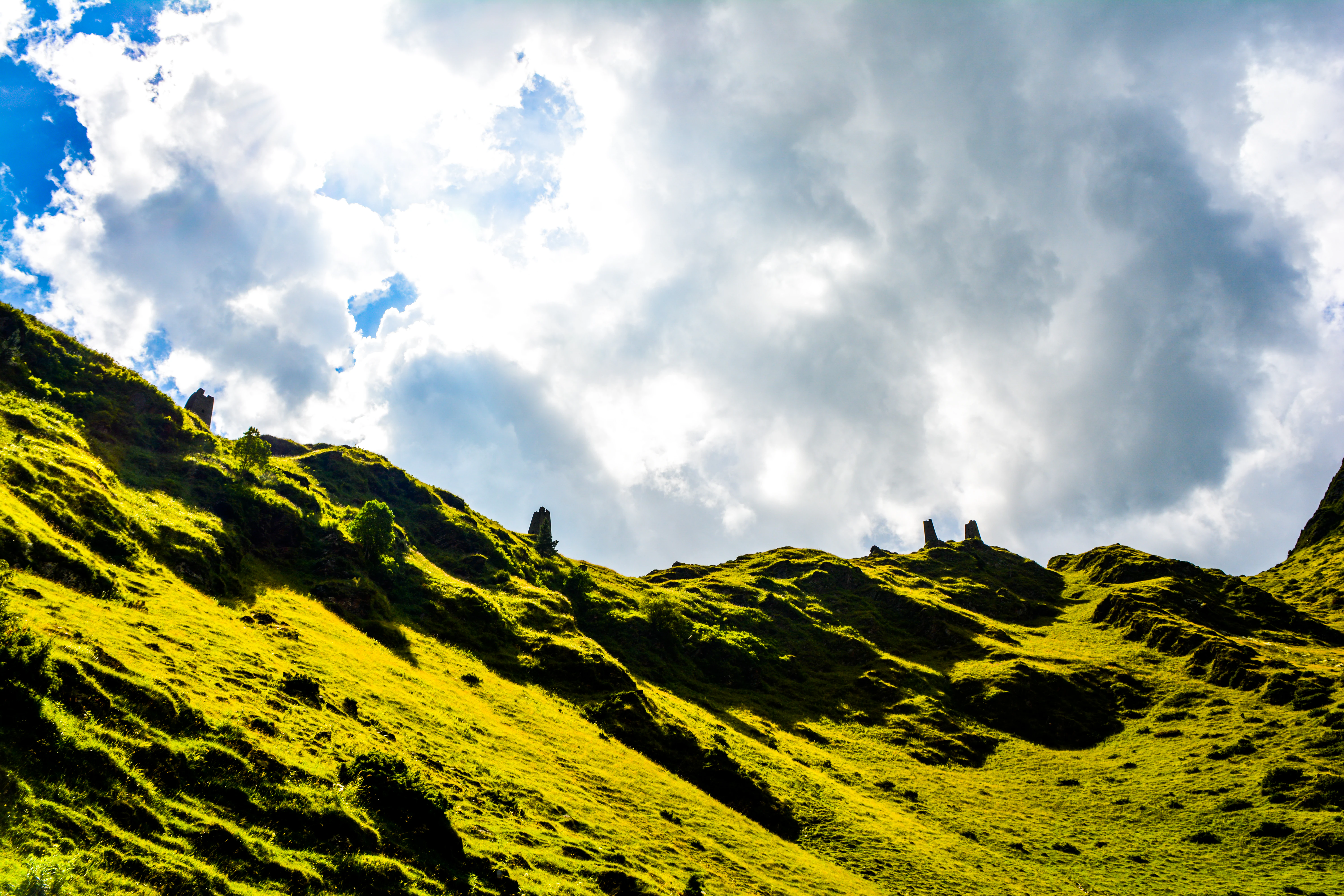 Green mountain slopes with scattered clouds in the sky