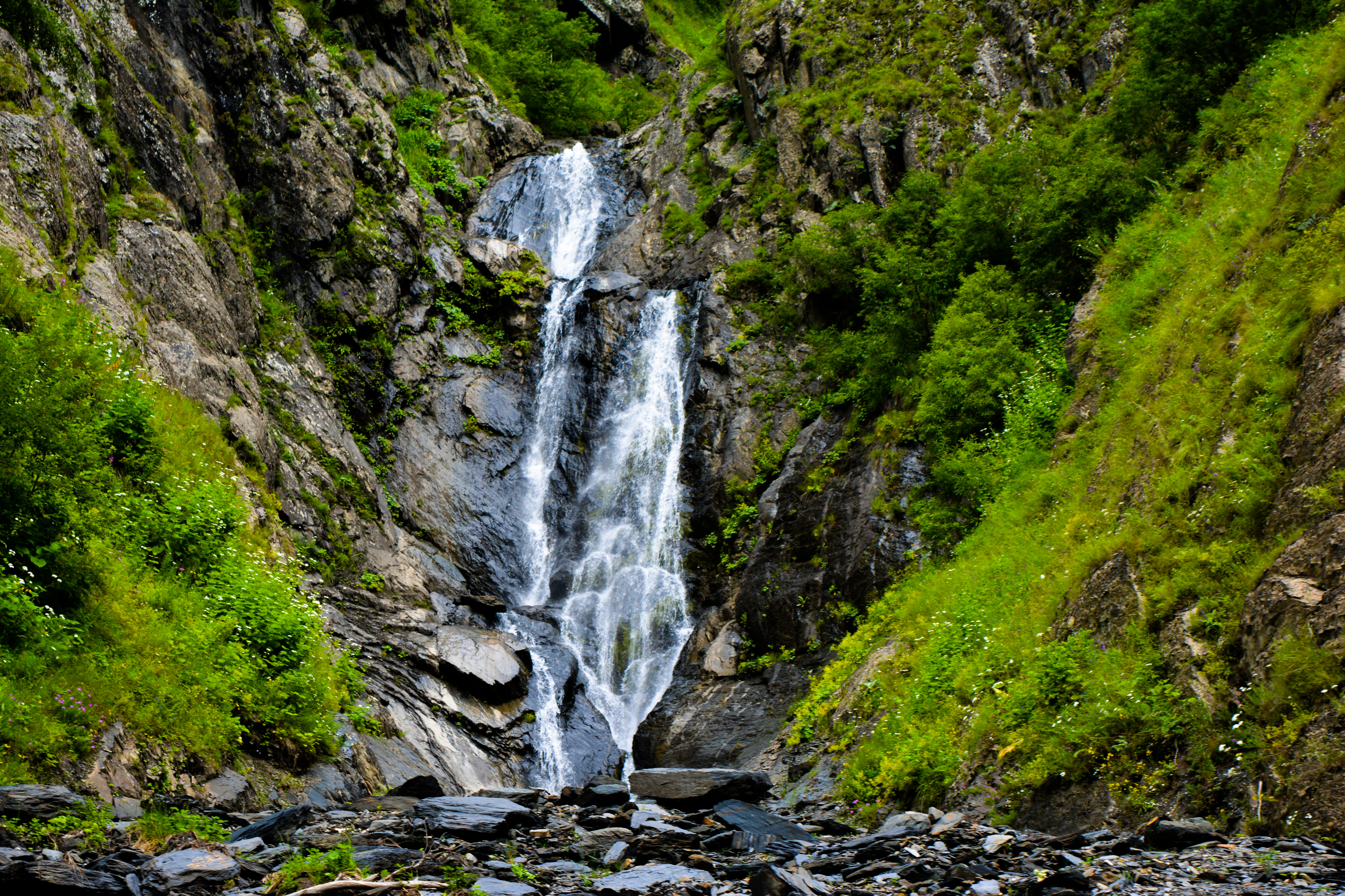 Waterfall cascading over rocky terrain with green vegetation on both sides