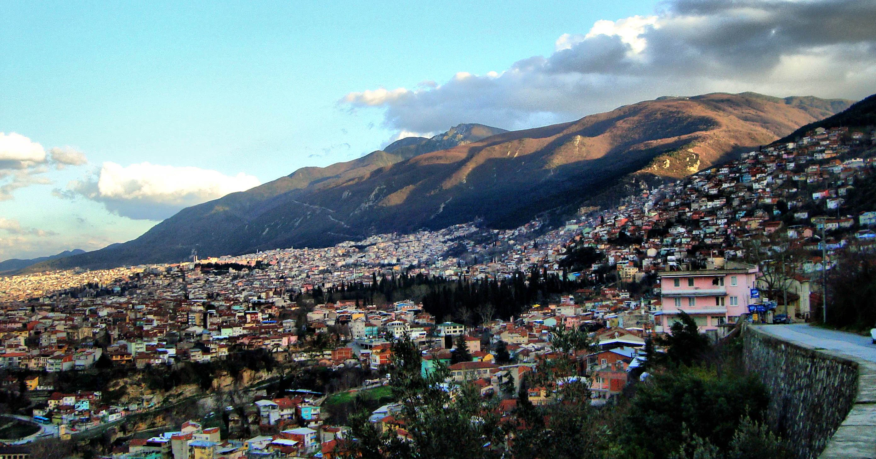 Panoramic view of Bursa city with mountains in the background under a partly cloudy sky