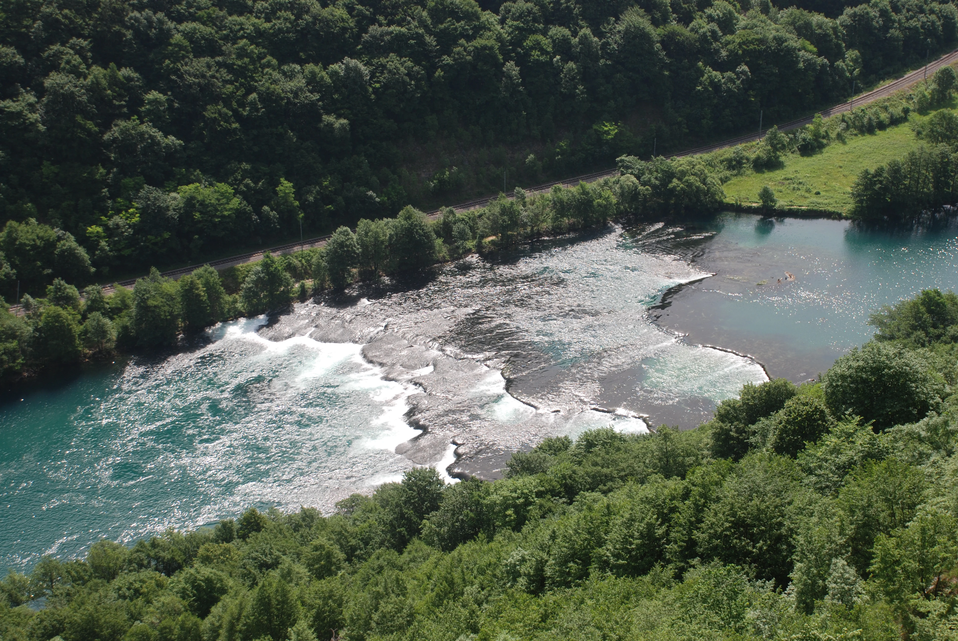 Aerial view of the Una River with turquoise water and white rapids surrounded by dense green forest