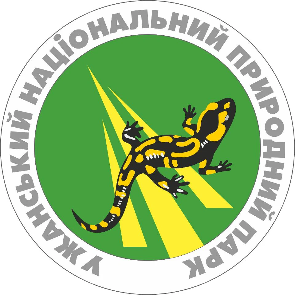 Green circular emblem with yellow stripes and a black-and-yellow salamander. Text in Ukrainian reads 'УЖАНСЬКИЙ НАЦІОНАЛЬНИЙ ПРИРОДНИЙ ПАРК'