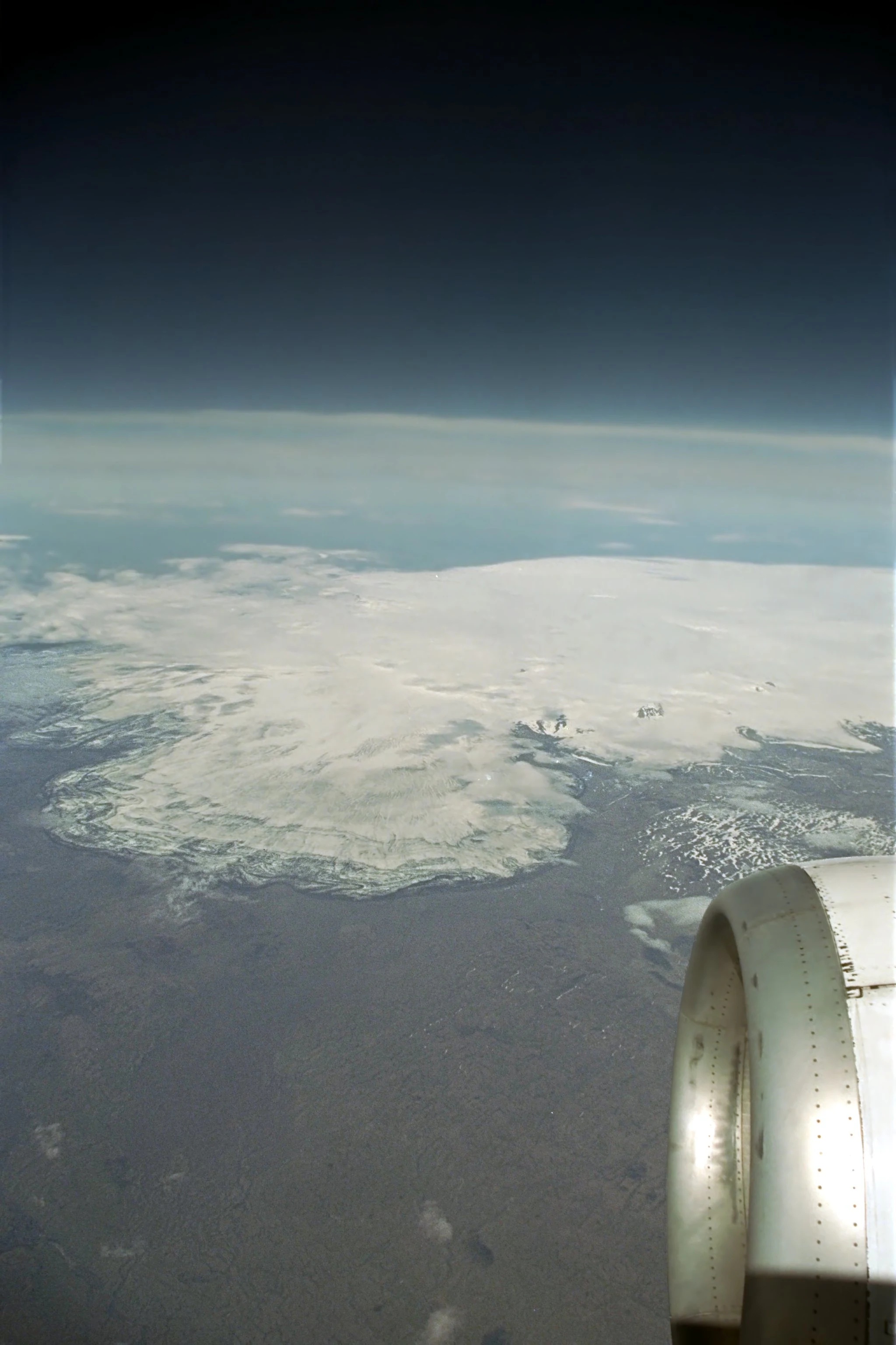 Aerial view from an airplane window showing Vatnajökull Glacier with visible aircraft engine on the right