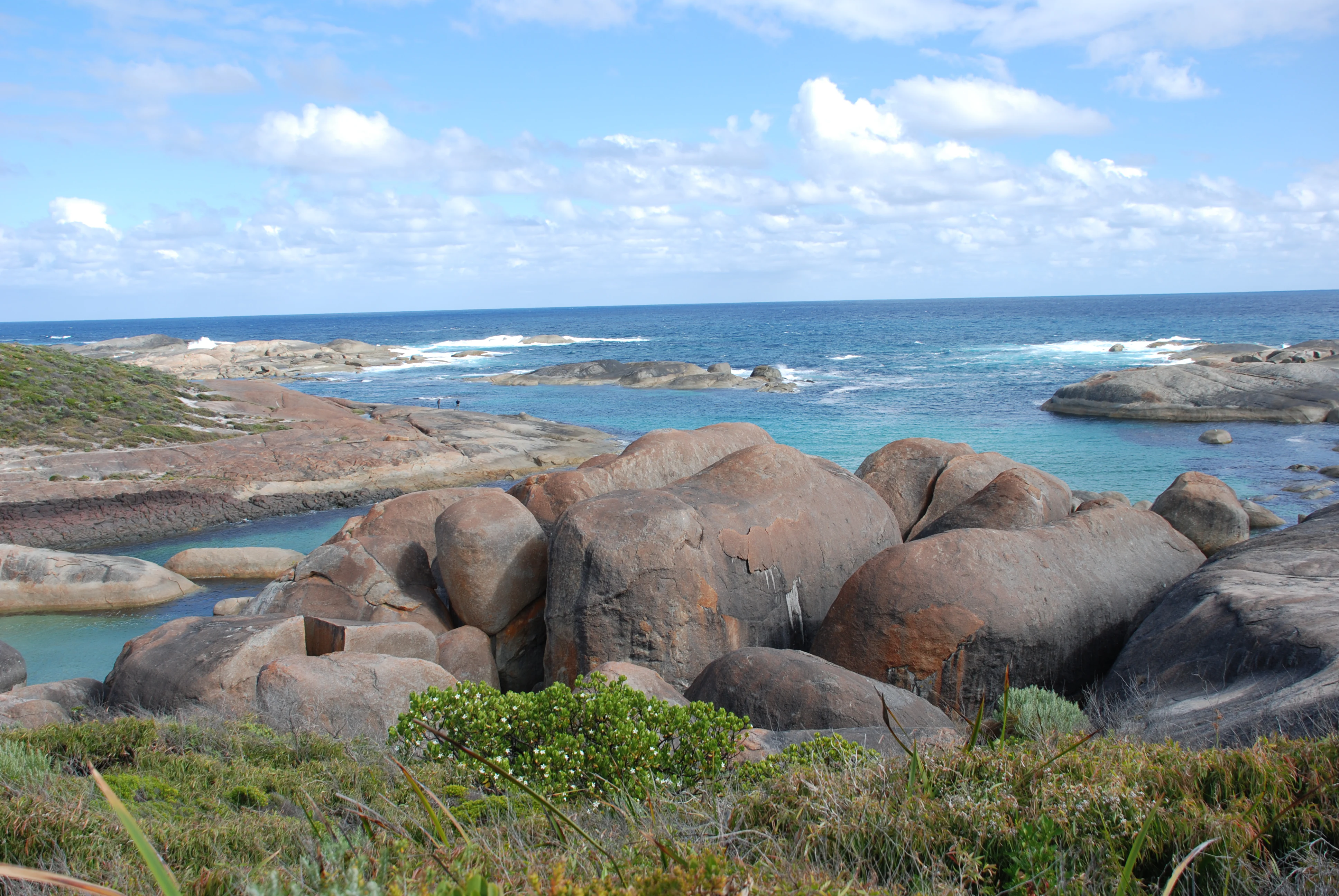 Granite boulders on a beach with ocean and sky in background