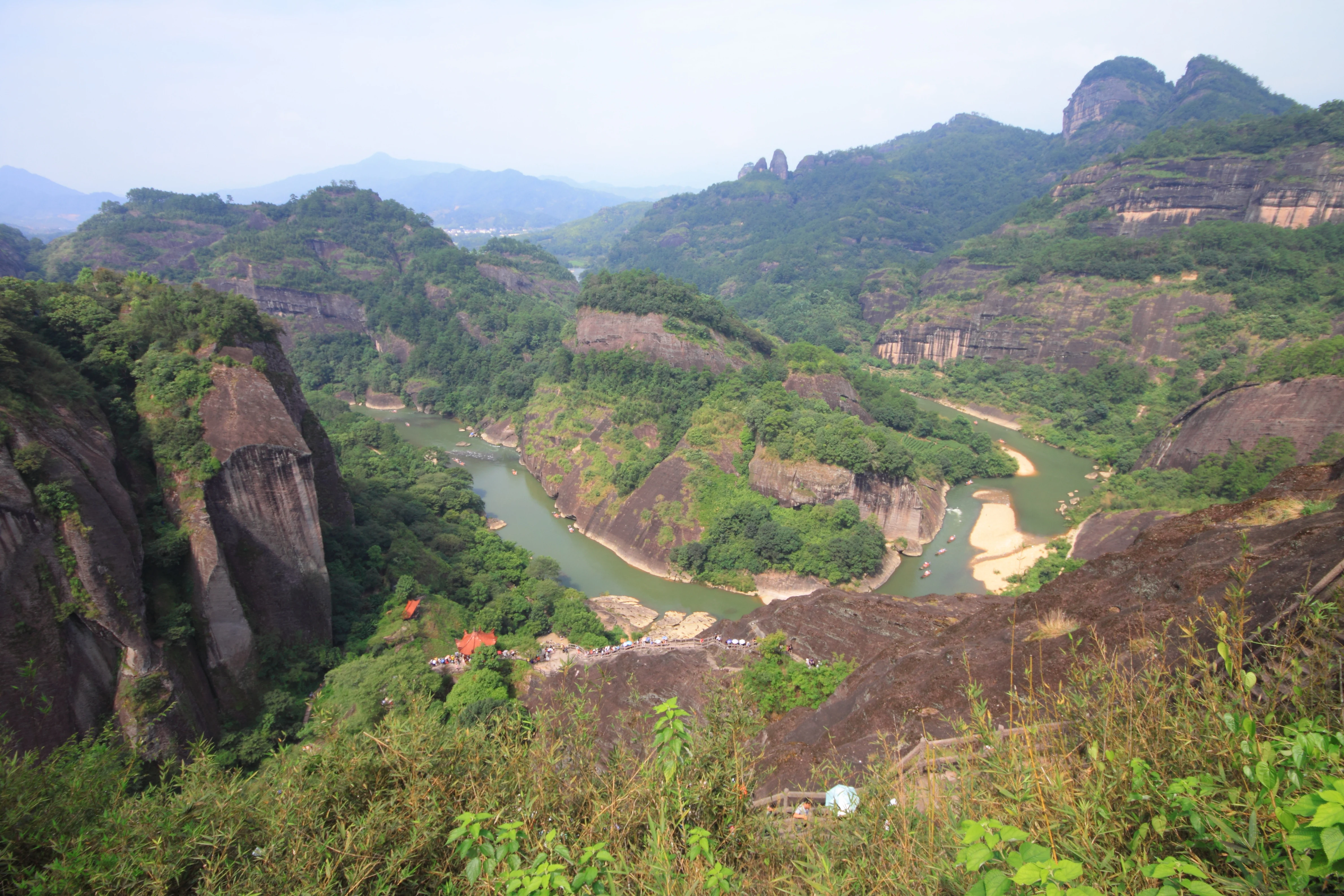 A high angle view looking down at a river curving through deep, green-covered rocky valleys and steep sandstone cliffs.