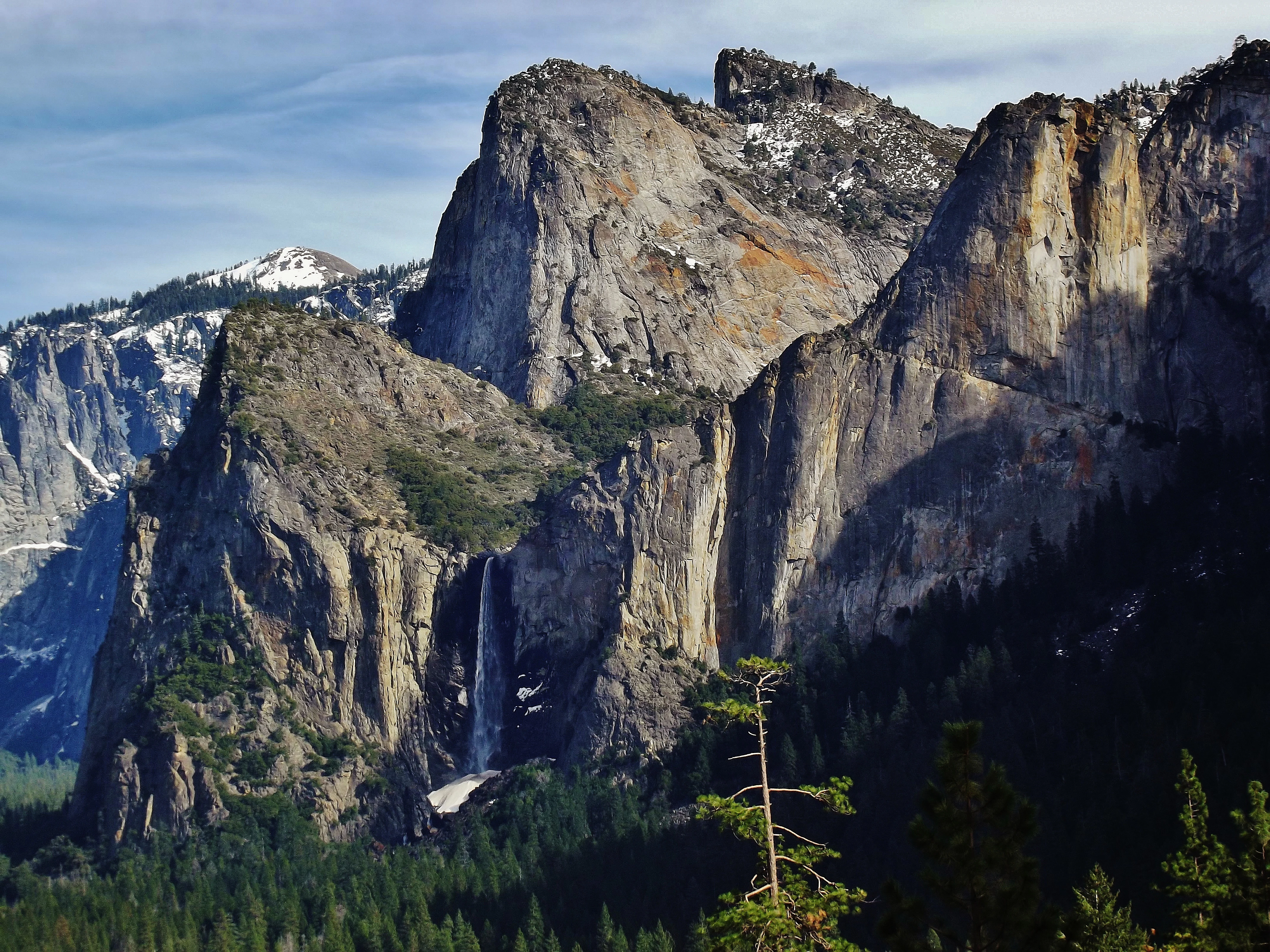 Bridalveil Fall waterfall flowing down granite cliffs with forested valley below