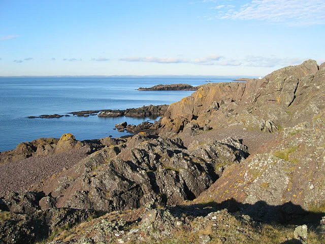 Rocky coastline with scattered islands in the distance, calm sea under a clear blue sky