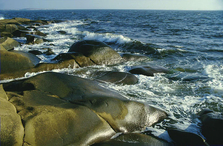 Rocky shoreline with waves crashing against large boulders in the ocean