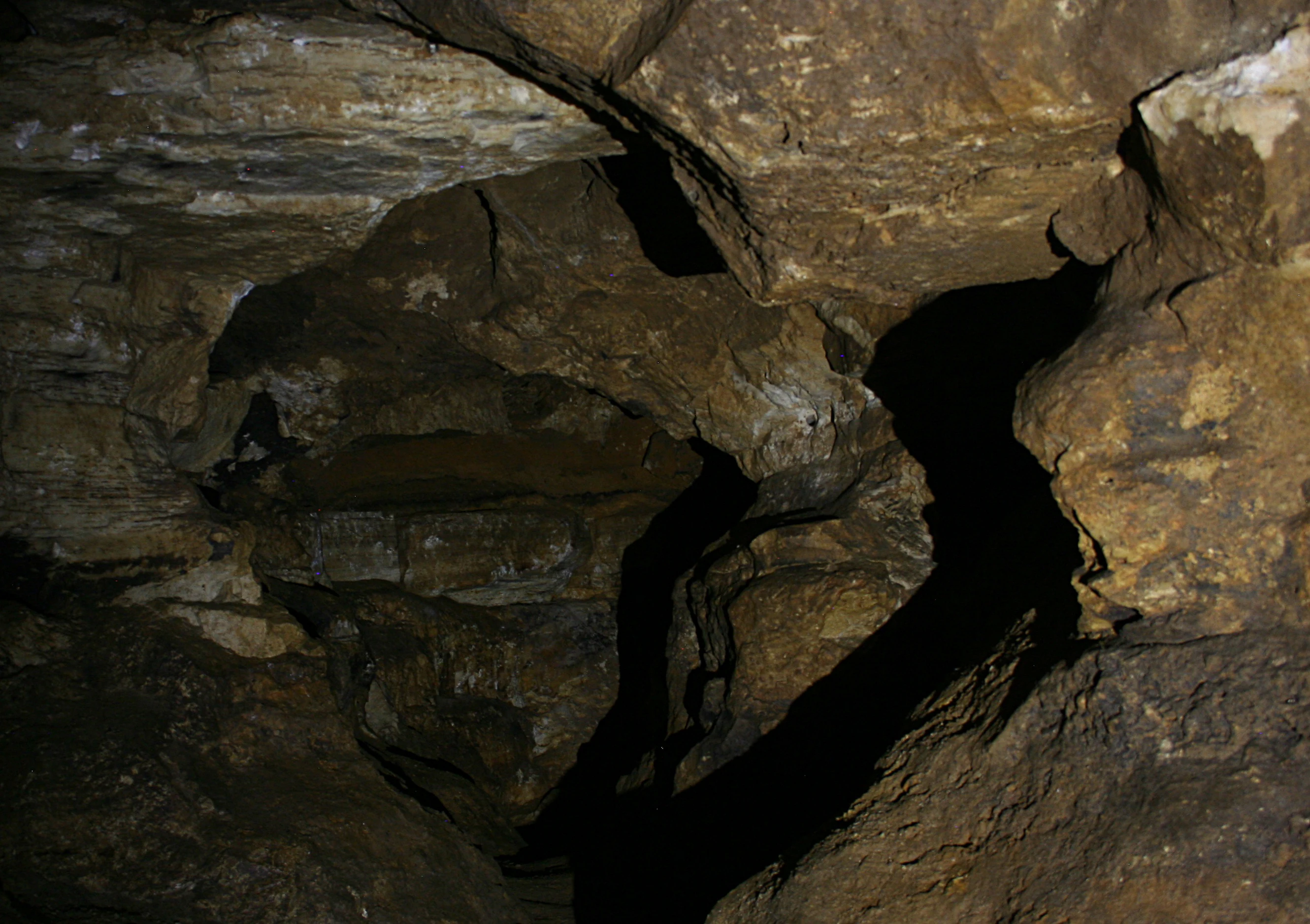 A view inside a limestone cave showing rocky walls and a narrow, dark winding passage.